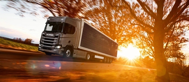 Caminhão movido a energia solar da Scania andando na estrada e ao fundo, uma forte luz do sol.