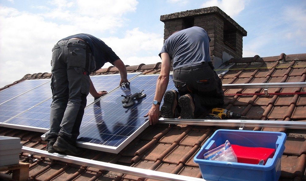 dois funcionários de uma grande empresa de energia solar instalando um sistema solar no telhado de uma residência