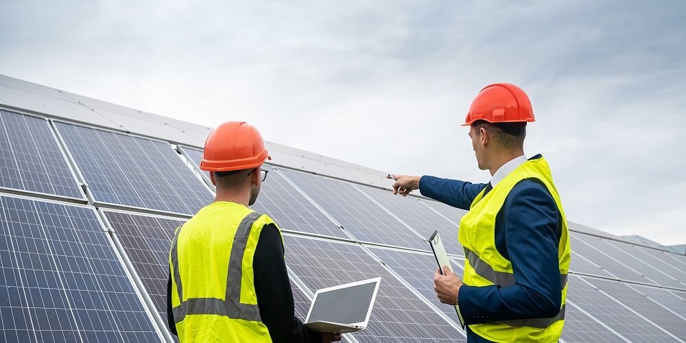 dois investidores analisando painéis fotovoltaicos adquiridos por uma franquia recém aberta de energia solar