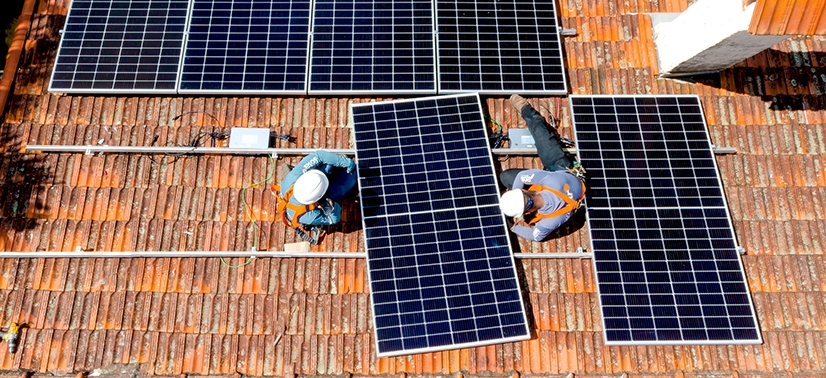 dois instaladores do Portal Solar apoiando a placa solar na estrutura de fixação
