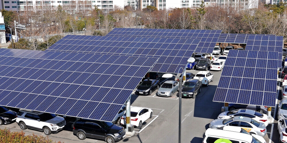 estacionamento com vários carros estacionados cujo a cobertura são de placas de energia solar fotovoltaica