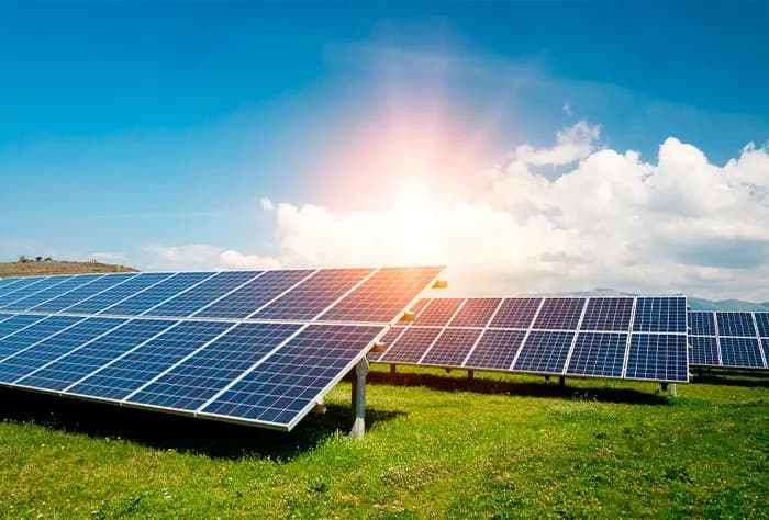 PLACAS SOLARES INSTALADAS EM CAMPO ABERTO COM CÉU AZUL E SOL BRILHANDO AO FUNDO