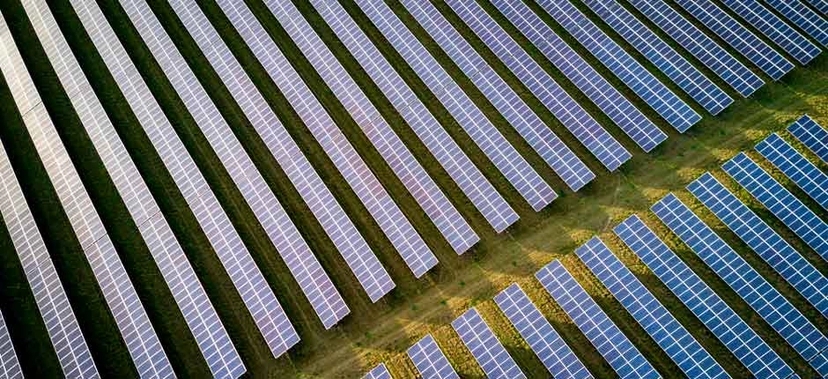VISTA AÉREA DE UMA USINA SOLAR COM FILEIRAS DE PAINÉIS FOTOVOLTAICOS INSTALADOS EM UM CAMPO
