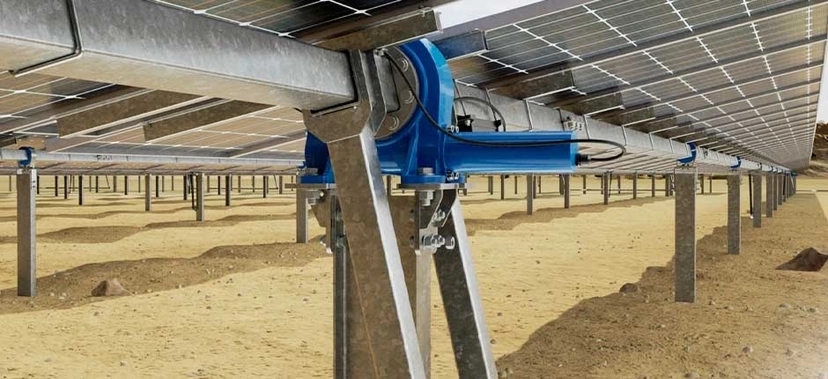 VISTA INFERIOR DE UMA ESTRUTURA DE RASTREAMENTO SOLAR (TRACKER), COM PAINÉIS FOTOVOLTAICOS MONTADOS SOBRE SUPORTES METÁLICOS AUTOMATIZADOS, INSTALADOS EM SOLO ARENOSO