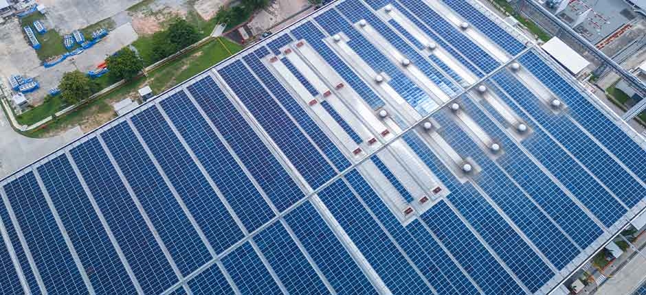 VISTA AÉREA DE UM GRANDE TELHADO INDUSTRIAL COBERTO POR PAINÉIS SOLARES FOTOVOLTAICOS