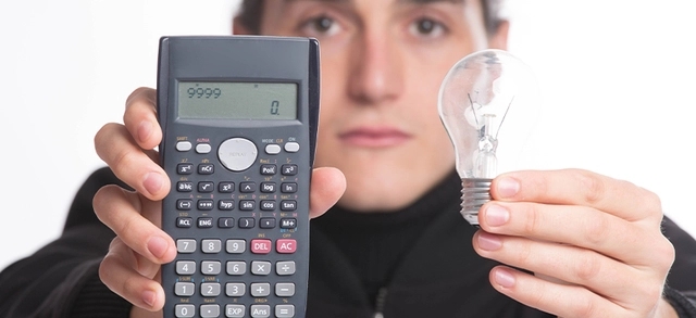 Pessoa segurando lâmpada e calculadora representando cálculo de consumo de energia elétrica