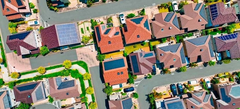 VISTA AÉREA DE UM BAIRRO RESIDENCIAL COM DIVERSAS CASAS EQUIPADAS COM PAINÉIS SOLARES NOS TELHADOS