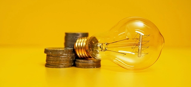 Lâmpada e moedas apoiadas em uma mesa