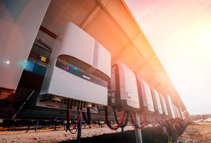 SÉRIE DE INVERSORES SOLARES INSTALADOS SOB PAINÉIS FOTOVOLTAICOS, CAPTANDO LUZ SOLAR INTENSA AO ENTARDECER