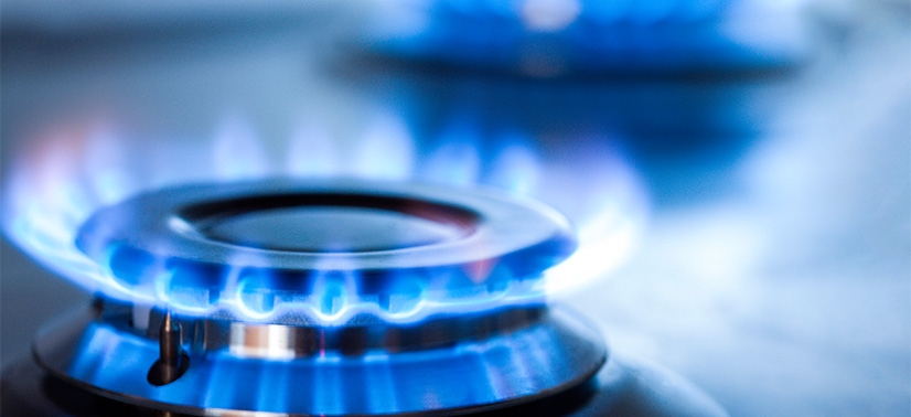 boca de um fogão de cozinha com uma chama azul acessa