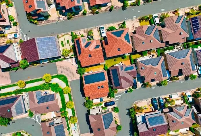 VISTA AÉREA DE UM BAIRRO RESIDENCIAL COM DIVERSAS CASAS EQUIPADAS COM PAINÉIS SOLARES NOS TELHADOS