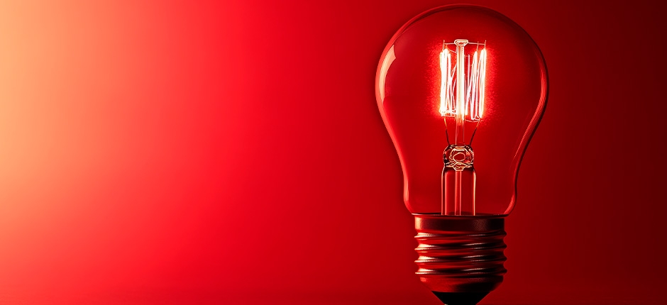 LÂMPADA INCANDESCENTE ACESA COM FUNDO VERMELHO EM DEGRADÊ