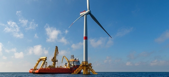 turbina eólica offshore instalada no mar logo ao lado da turbina, há um grande navio especializado em construção e manutenção de parques eólicos offshore