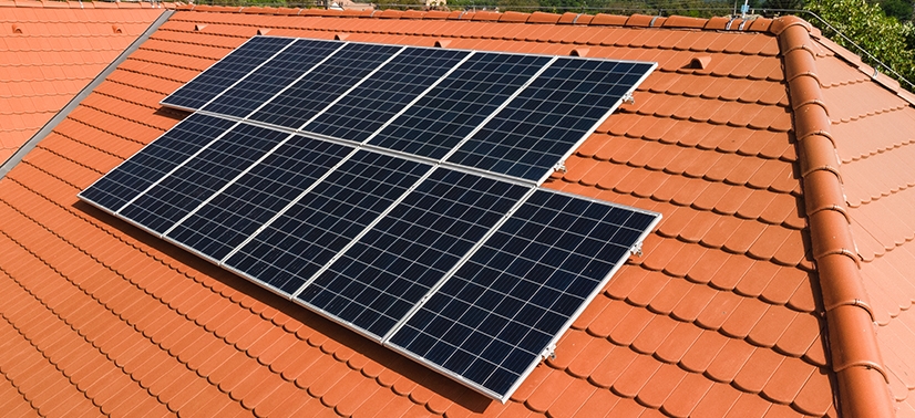 placas de energia solar sob o telhado de uma residência e ao fundo o céu