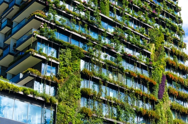 edifício com uma fachada verde, onde plantas e vegetação estão integradas à estrutura do prédio