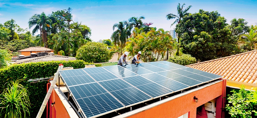 linda casa com plantas plantas ao lado e dois instaladores realizando a implementação de um si\stema de energia solar residencial