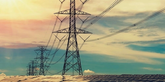 torres de transmissão de eletricidade em um campo e ao fundo céu com nuvens e luz do sol