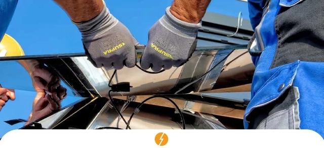 mãos de dois instaladores de energia solar realizando um serviço de instalação em uma empresa