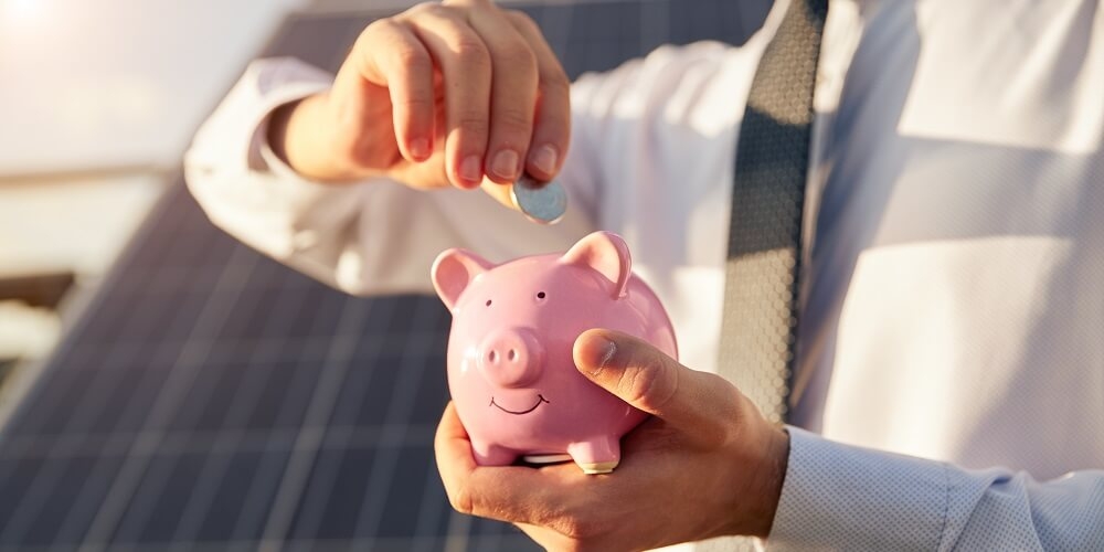 pessoa prestes a inserir uma moeda dentro de um porquinho rosa, dando a intenção de guardar dinheiro
