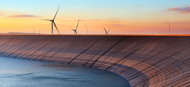 represa com torres eólicas ao fundo