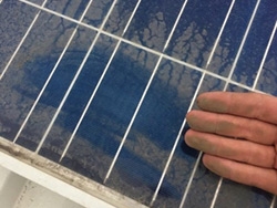 mão de uma pessoa suja de poeira após passar a mão em um painel solar